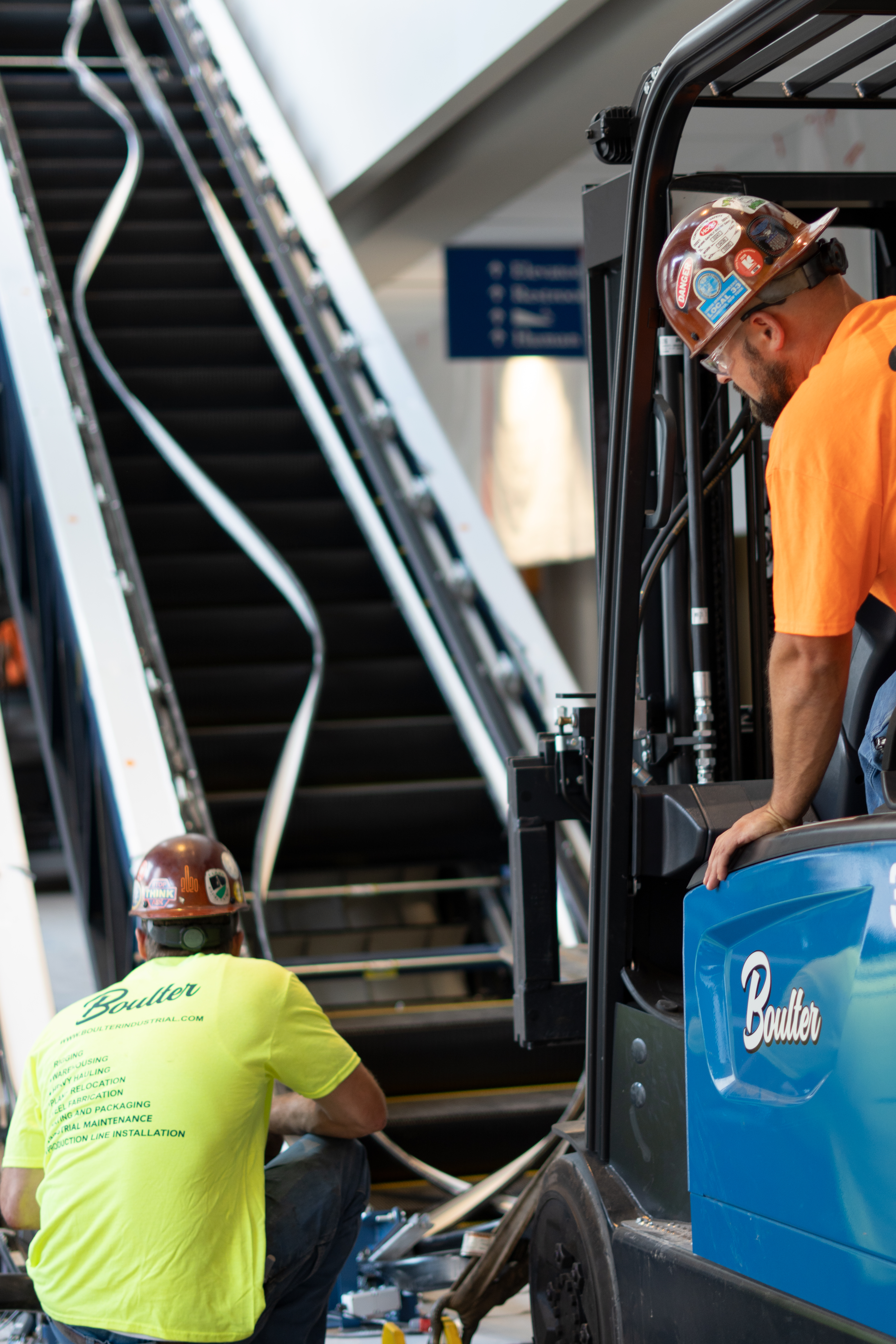 Lifting an escalator using slings and forklifts to set it in place