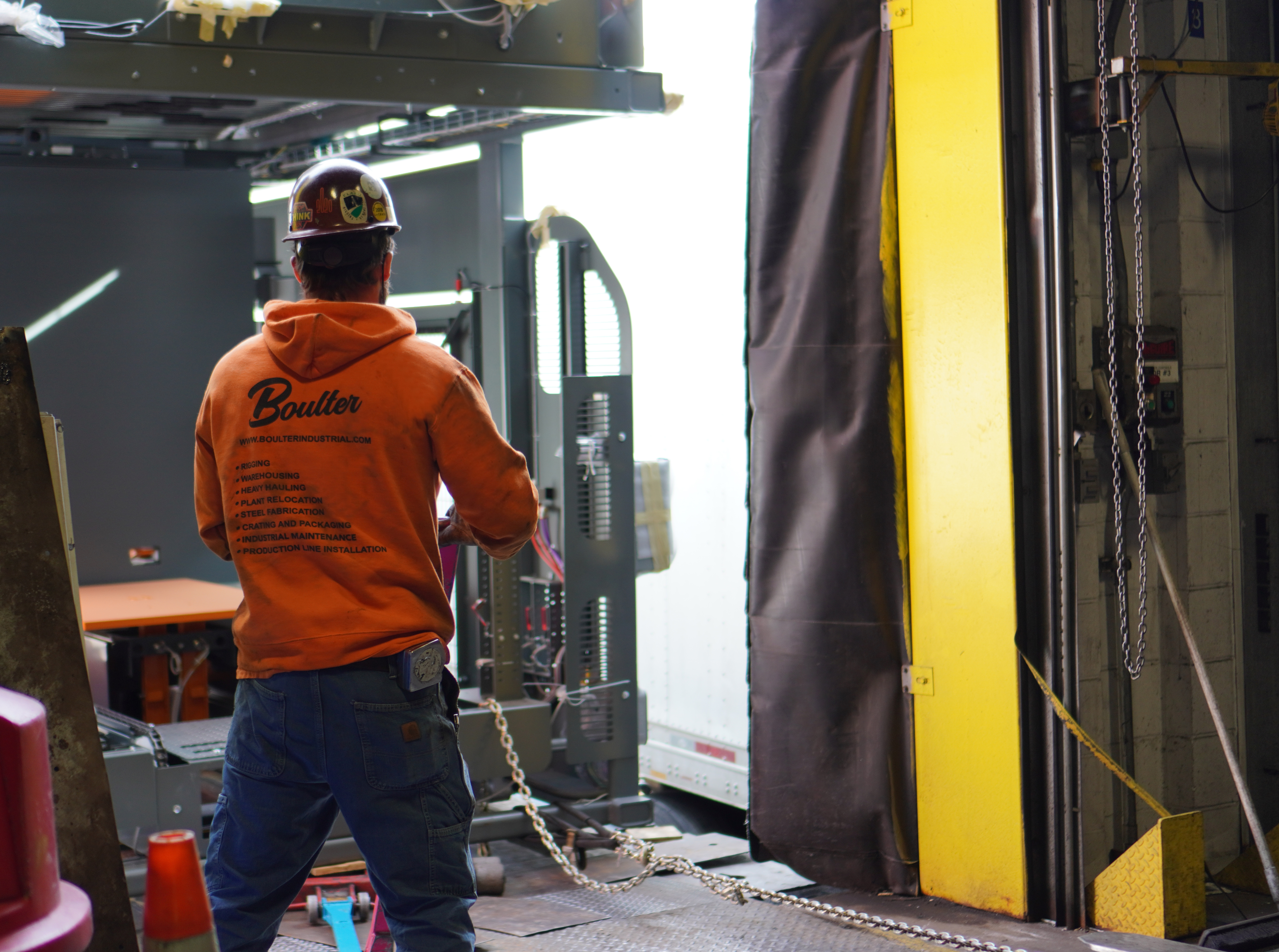 Millwright using skate system to guide large palletizer inside Genesee Brewery