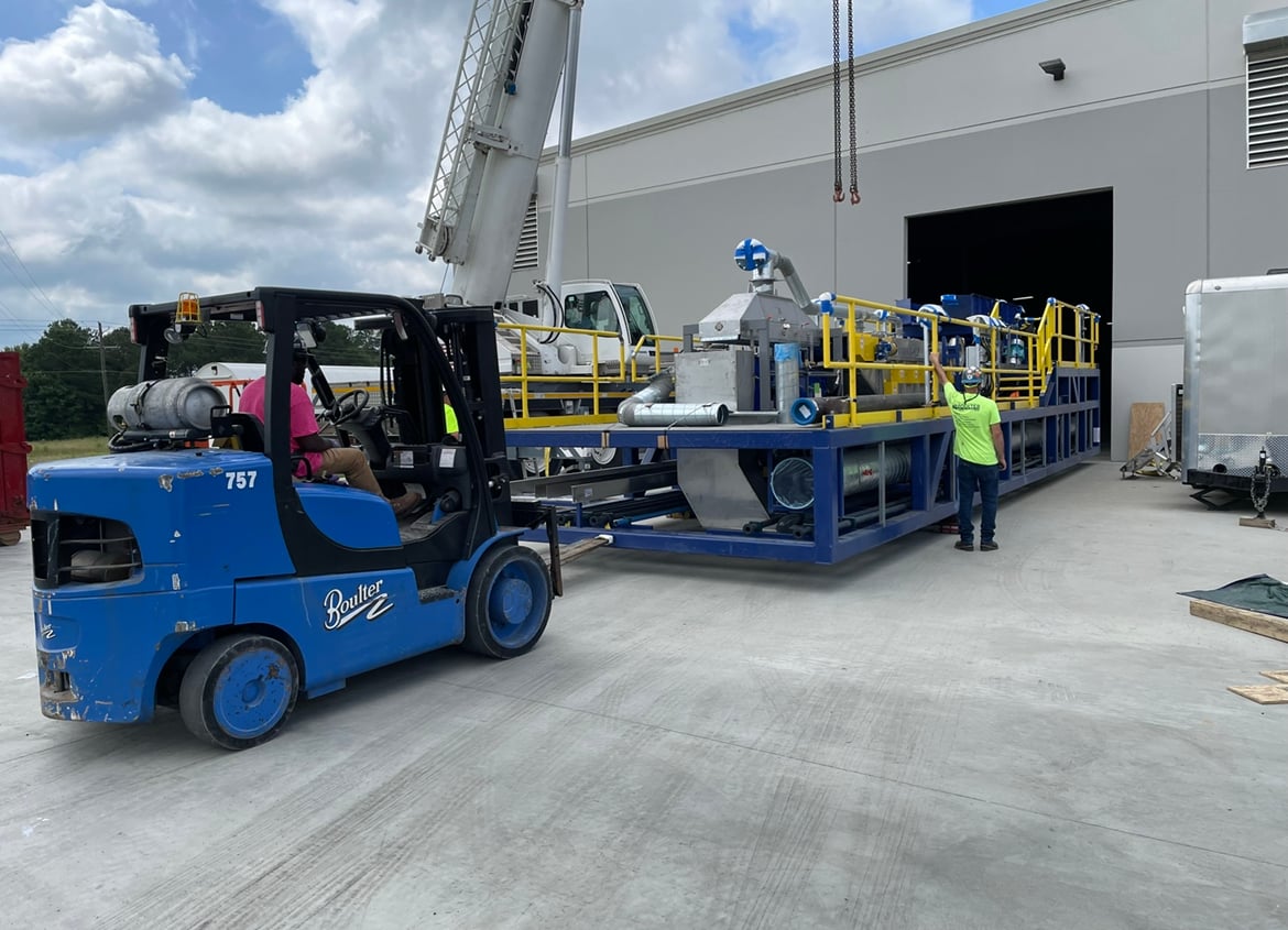Forklift and crane guiding processing equipment into Li-Cycle's Alabama Spoke facility